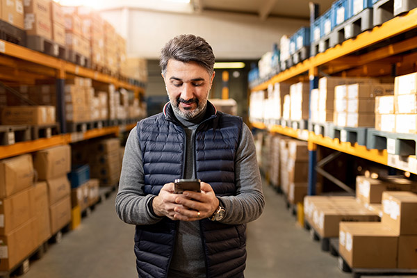 man standing in a warehouse looking at his mobile phone
