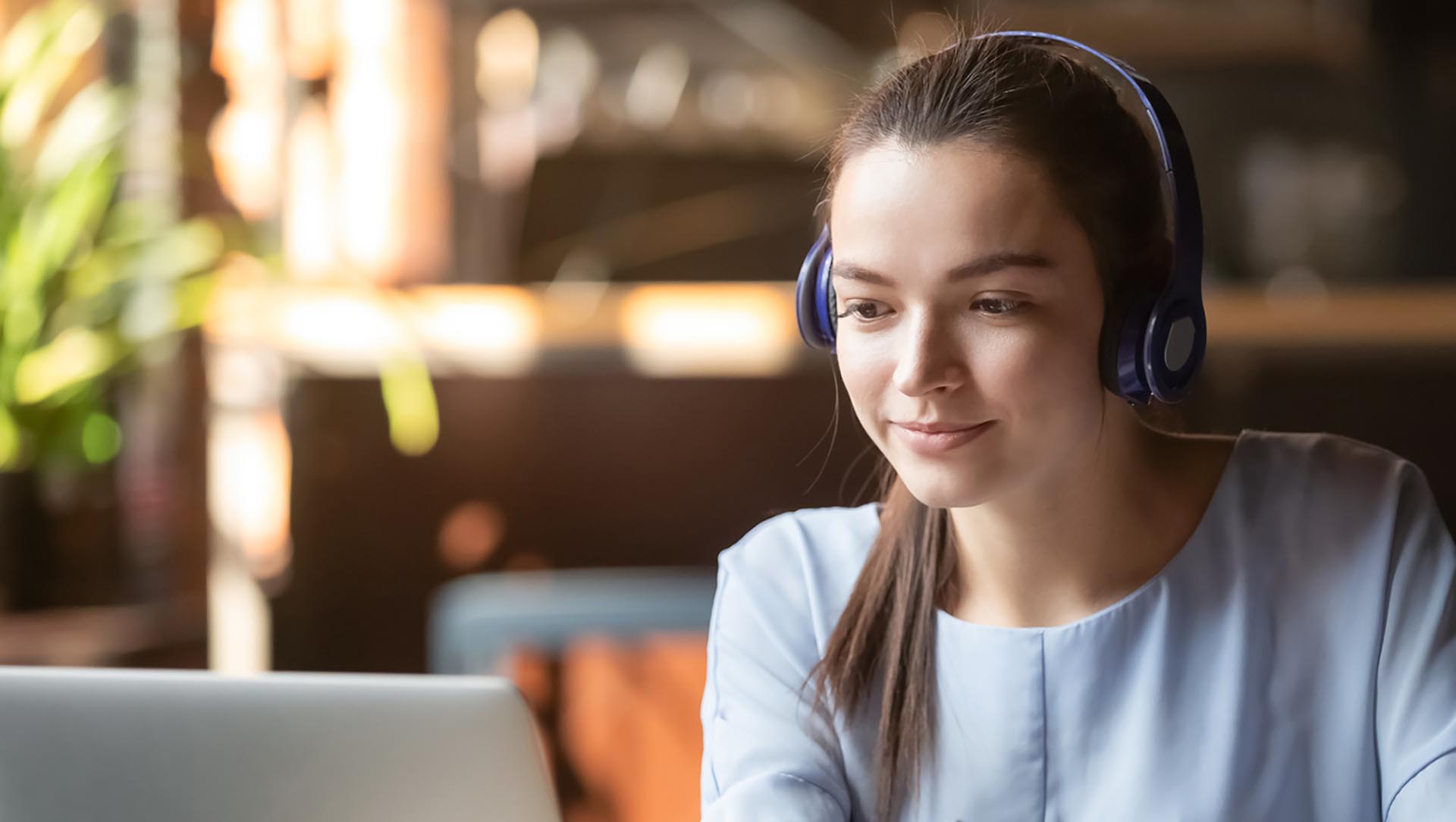 a young woman wearing headphones looking at a laptop