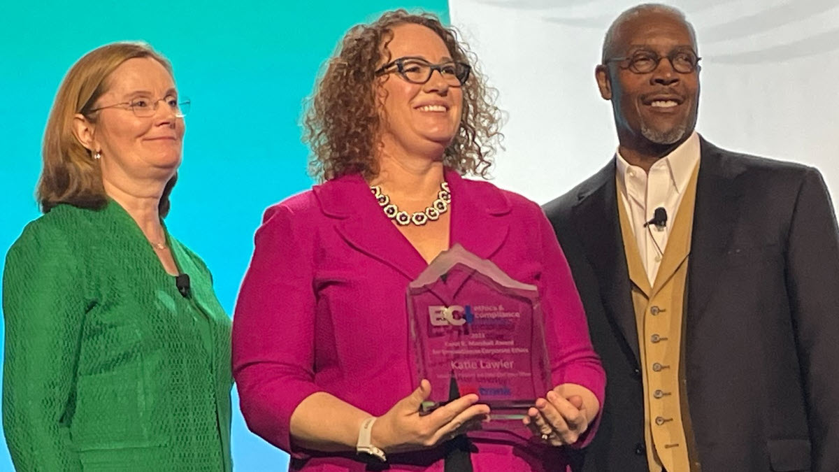 Image of three people, with Amy Lawler in the center holding her award.