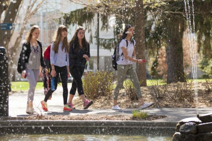 Four female college students walking through campus.