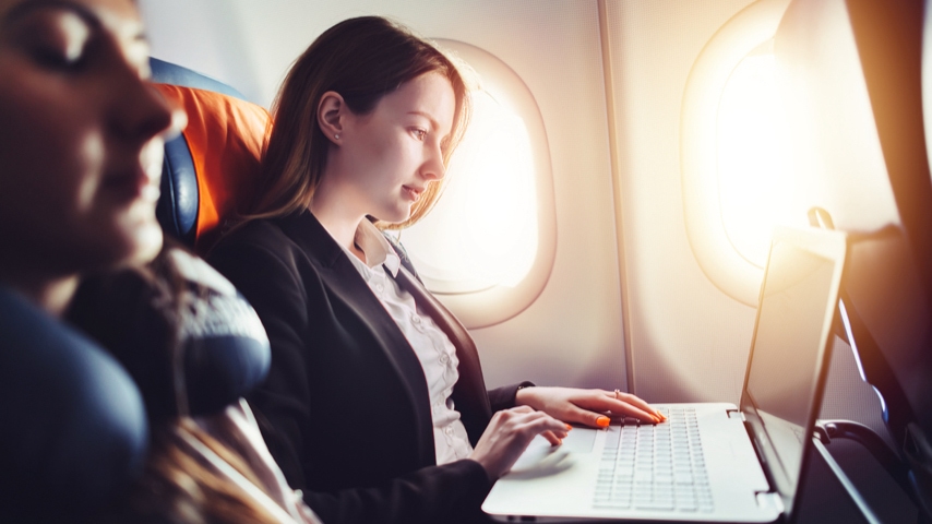 Person sitting in an airplane while using a laptop