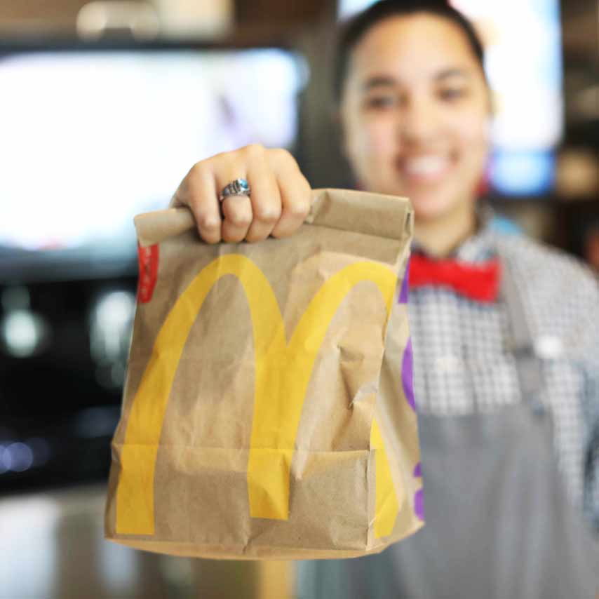 Picture of McDonald’s employee handing a McDonald’s bag to a customer.