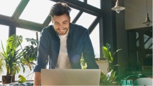 Man at home smiling at his laptop
