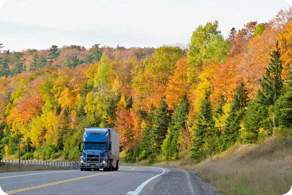 Photo of semi truck driving through autumn landscape