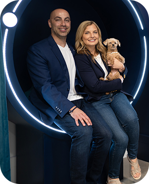 Man and woman sitting together and holding a small dog.