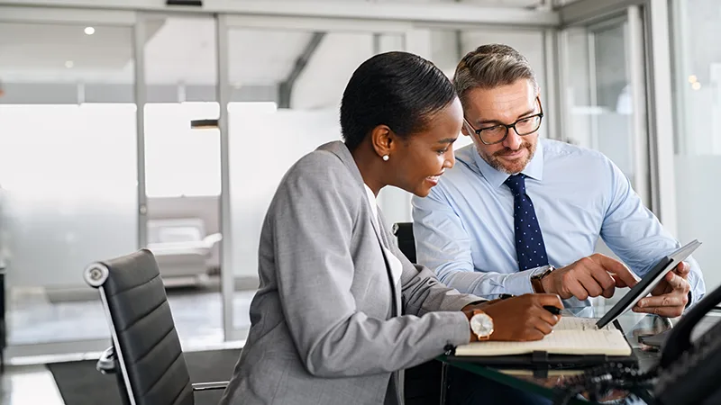 Two office colleagues looking at tablet discussing how to improve the digital payments experience with AP automation.