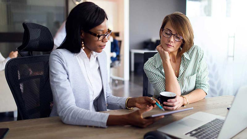 Two women look over cross border payments on a tablet