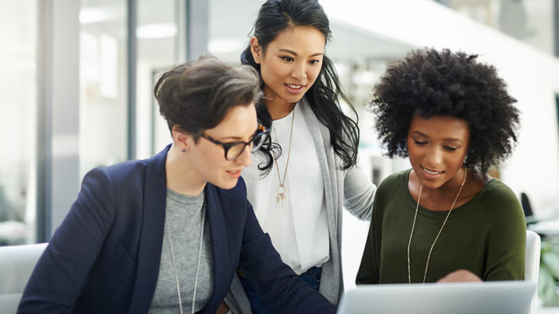 Three business women looking at international cash flow on a computer
