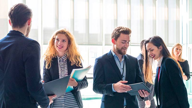Office workers standing around a conference room discussing global custody account services network.