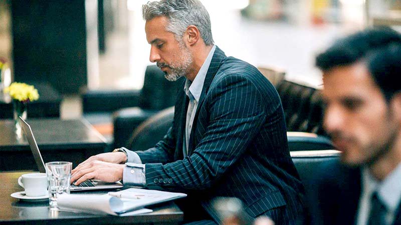 Man wearing suit researching alternative funds on his computer. 