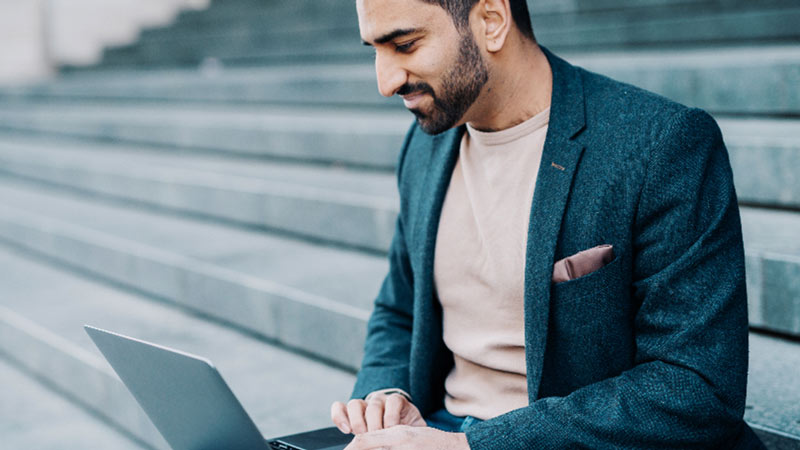Man on computer looking up banks that can do cryptocurrency custody.