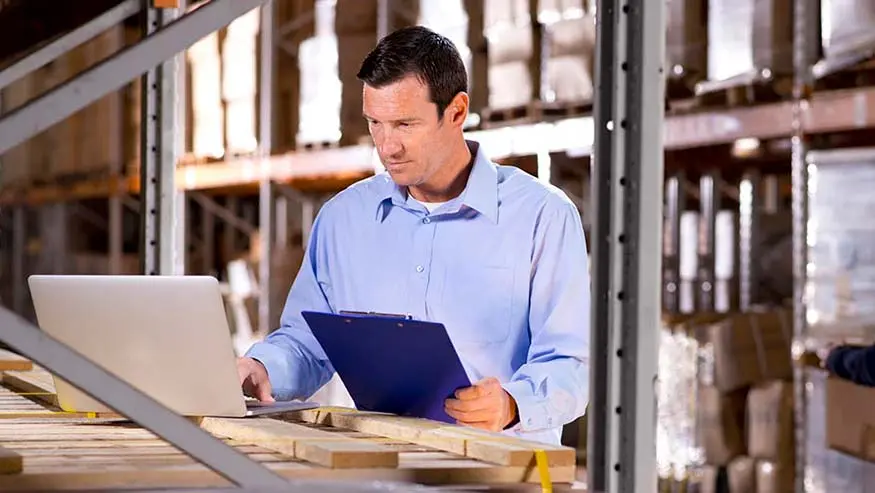 Man holding clipboard in one hand and typing on his laptop with the other as he searches for ABL options