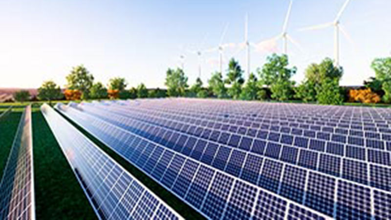 Solar panels in a field and windmills in the background