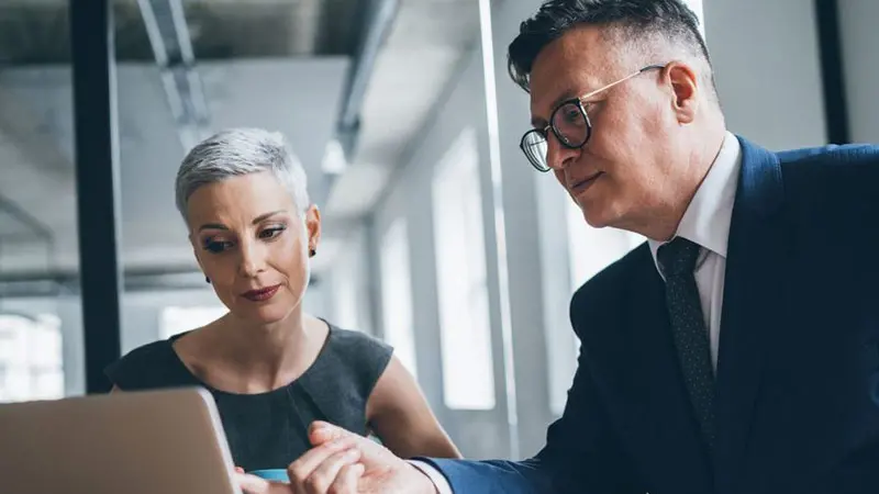 Two business people pointing at a laptop screen