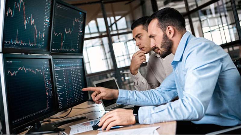 Two men looking at international payment graphs and comparing ach vs wire transfer.