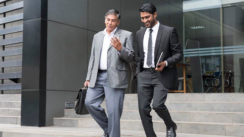 Two businessmen walking out of building discussing what are exchange traded funds and the advantages and benefits of them.