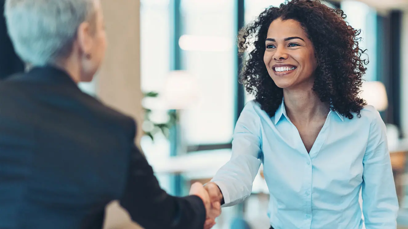 Man and woman in office shaking hands after discussing financial custodian services.