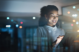 Woman in a dark room browsing on her laptop