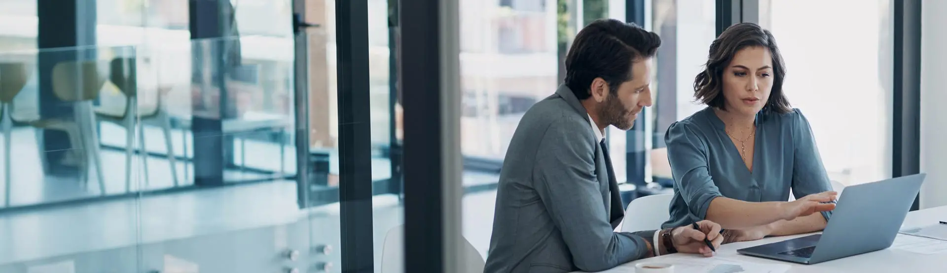 Professional man and woman looking at a laptop in a board room