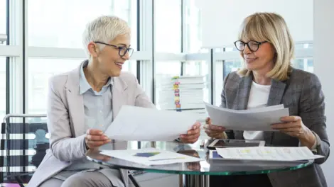 Two businesswoman share paperwork in an office