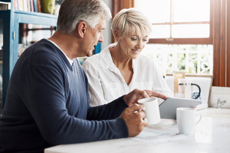 Couple in their kitchen reviewing banking options on iPad