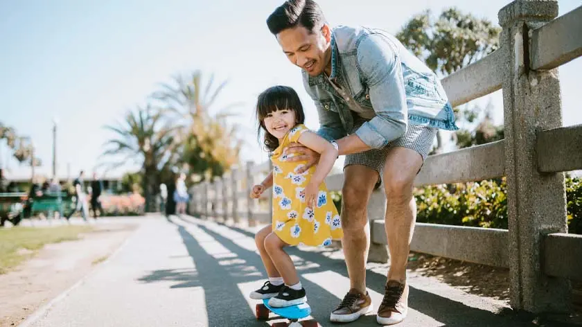 father helping daughter ride a bike