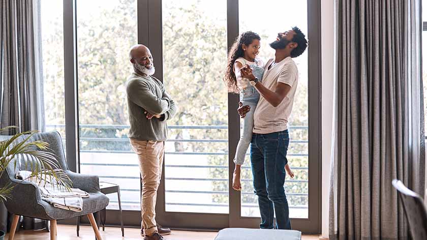 Father holding his daughter and laughing while grandfather looks on