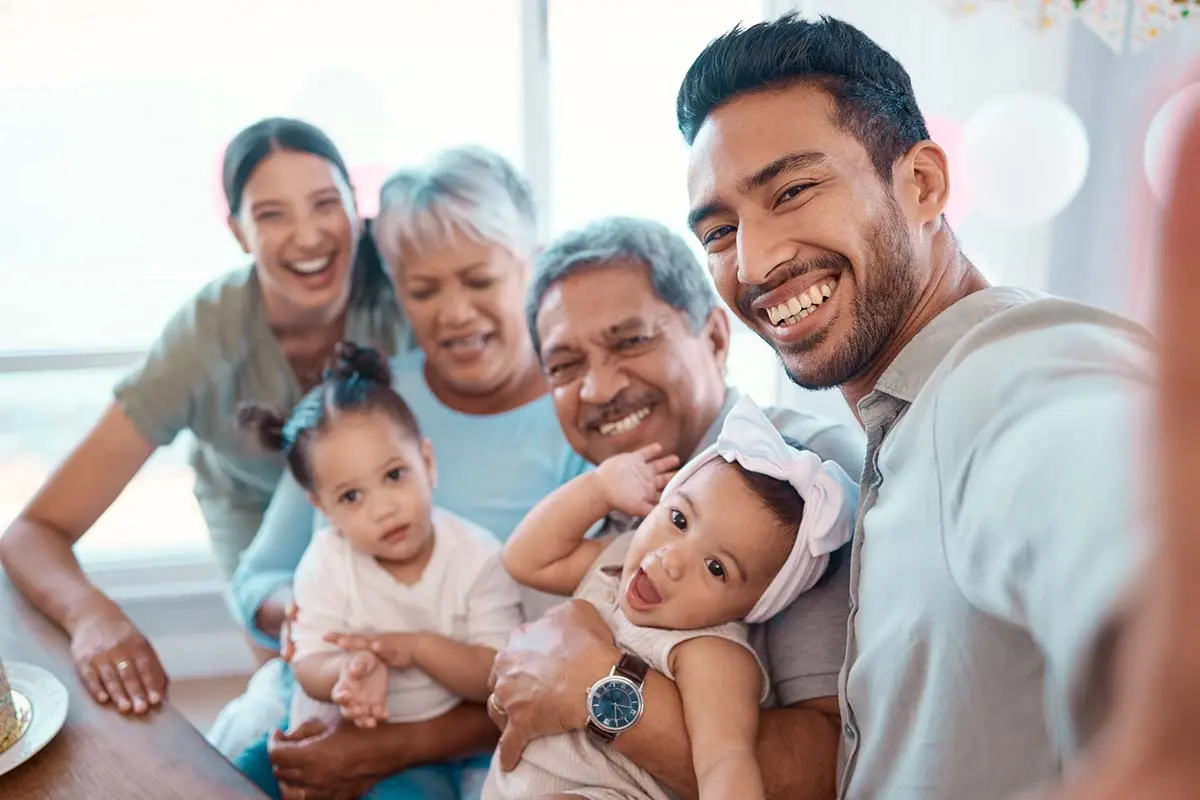 A happy family portrait with three adults and two young children smiling together. 