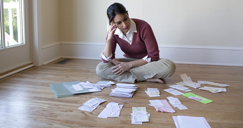 Woman sitting crossed-legged on floor, papers spread out before her. 