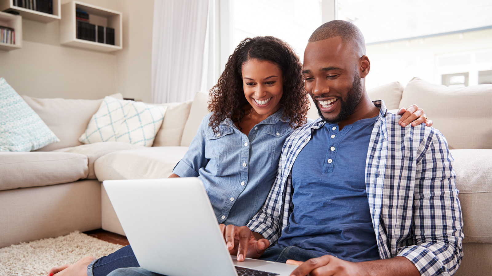 couple smiling and looking at a laptop