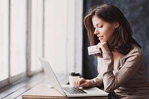 woman holding a credit card and looking at a laptop