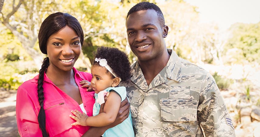 Military family with a young daughter, smiling at camera. 