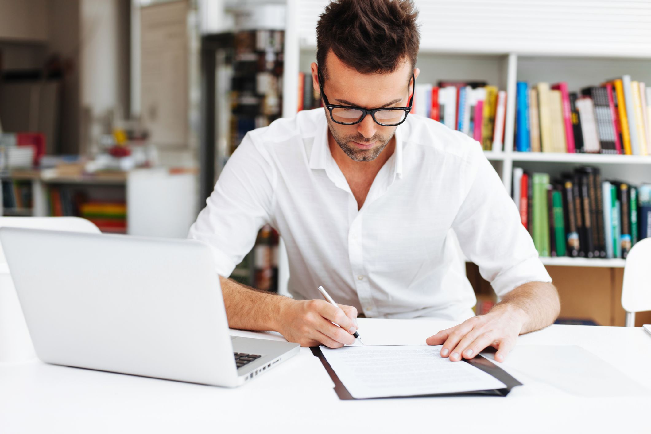 Man going over papers, sitting in front of laptop