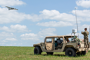 Photo of a military Humvee with a plane flying overhead