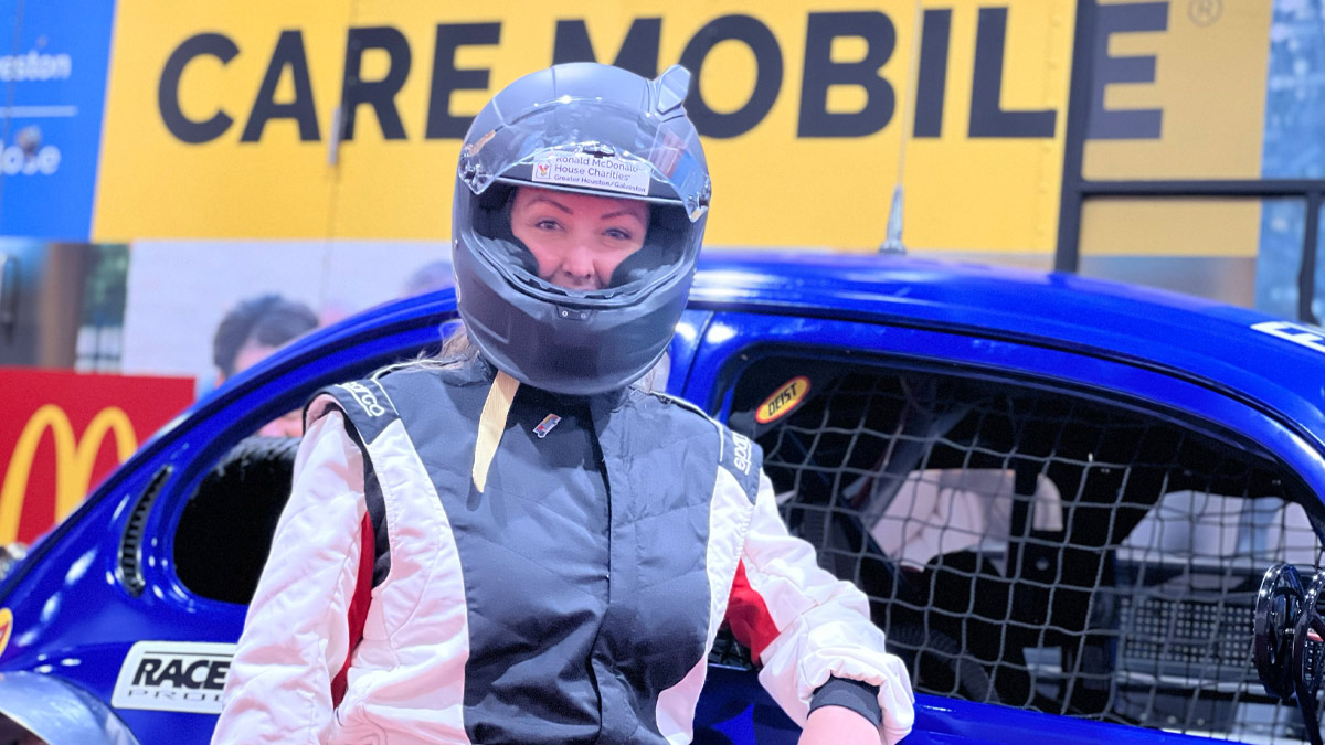 Photo of Alma Winkel wearing racing helmet and standing in front of race car.