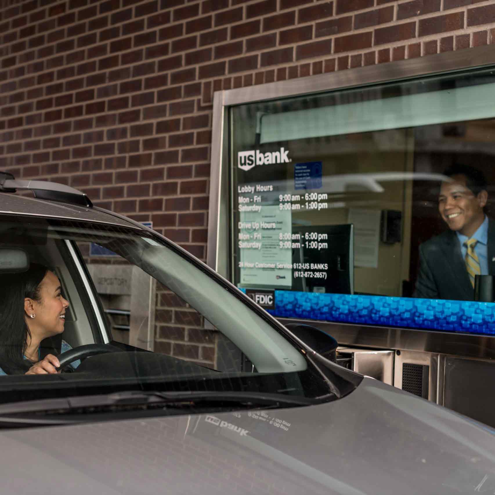 U.S. Bank employee and customer smile during a drive-up transaction