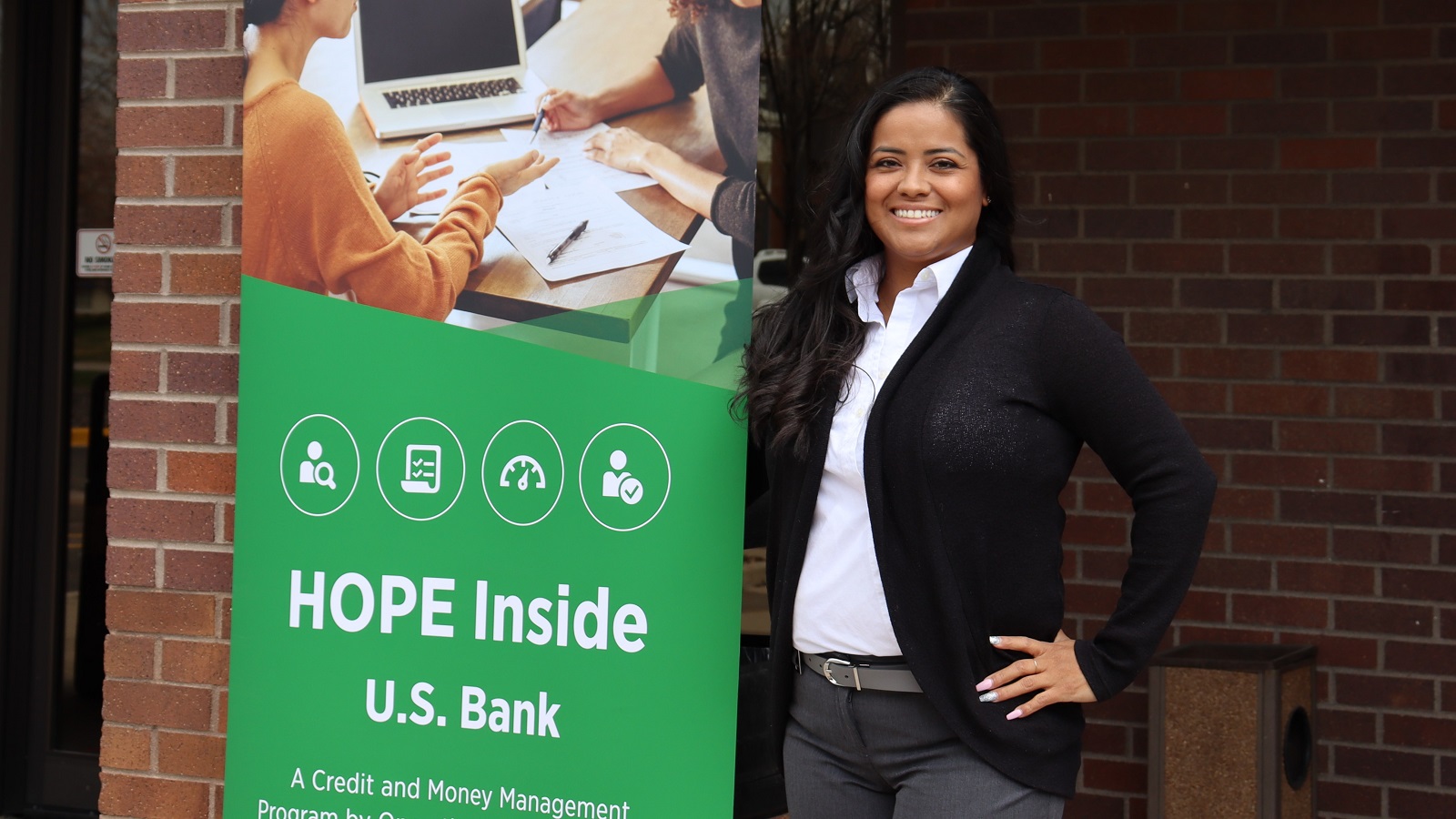 U.S. Bank financial wellbeing coach Laura Villalpando standing by a HOPE Inside banner.