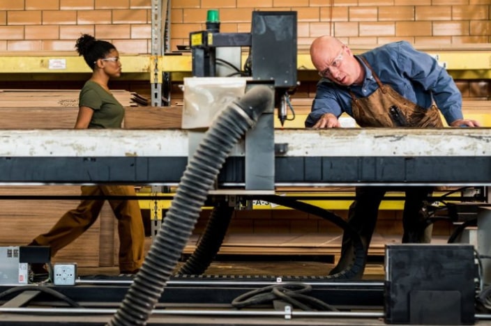 Man using a large piece of industrial equipment to shape a piece of metal.