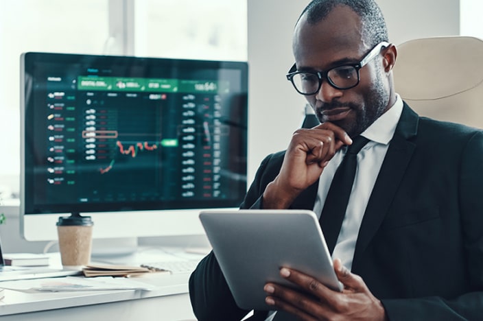 Businessman wearing glasses, suit and tie looking financial charts on his computer.