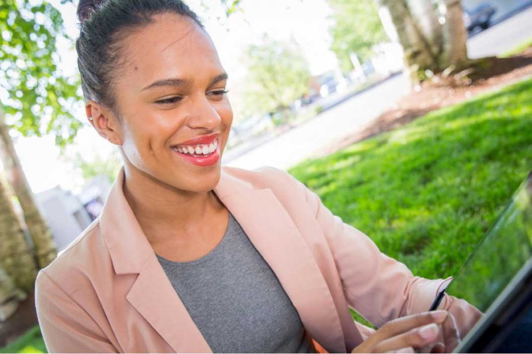 Smiling woman sitting outdoors and using a mobile device