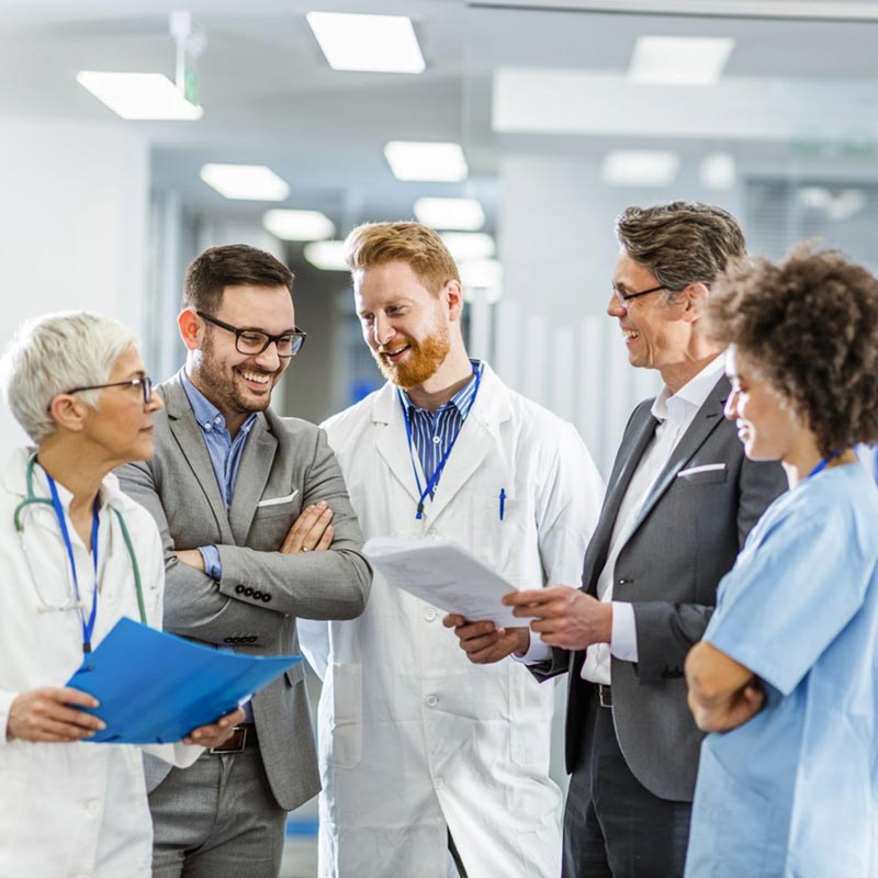 Five healthcare and business professionals standing together and discussing finances.