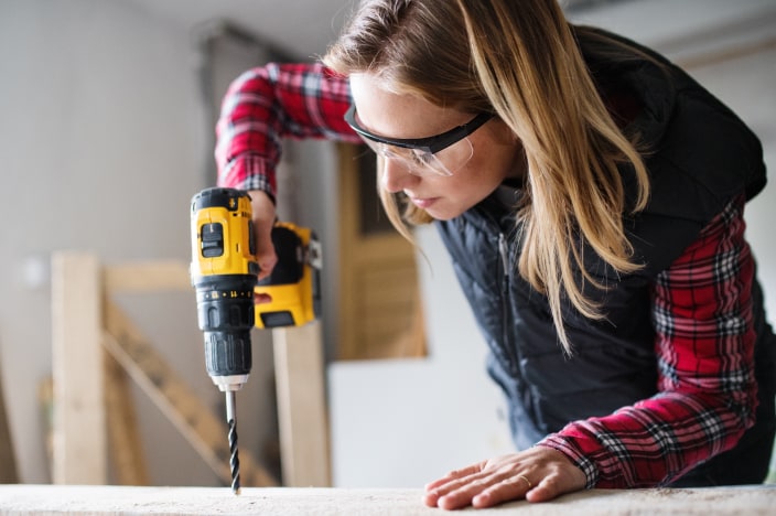 Woman wearing safety glasses working with a drill