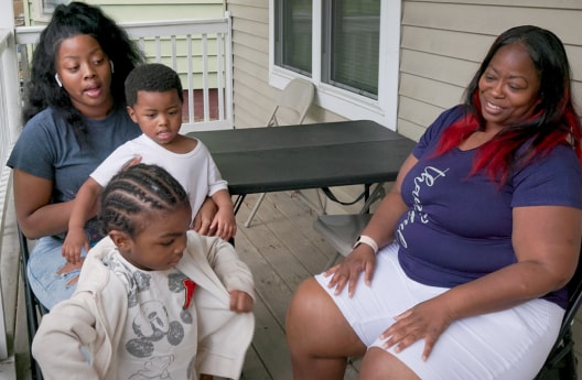 Melody Jones and her family members sitting outside the home she purchased with help from U.S. Bank
