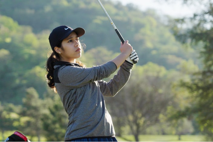 Young female golfer holding a club and taking a swing