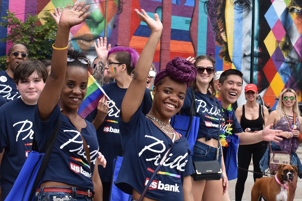 A group of people wearing U.S. Bank Pride shirts celebrate at a festival.