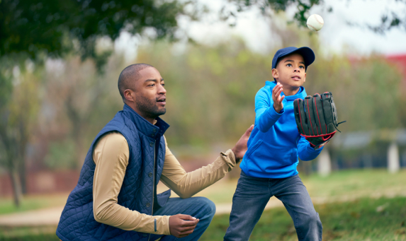 man and boy playing baseball in a park